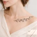 Tatuagem feminina na clavícula com galho floral e toque elegante