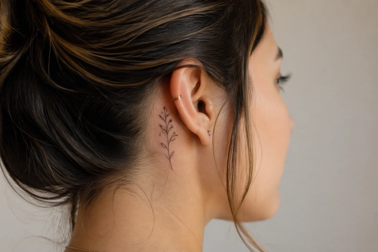 Tatuagem feminina delicada atrás da orelha com traço fine line floral