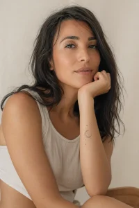 Mulher com tatuagem delicada de lua e estrelas no antebraço em estilo fine line