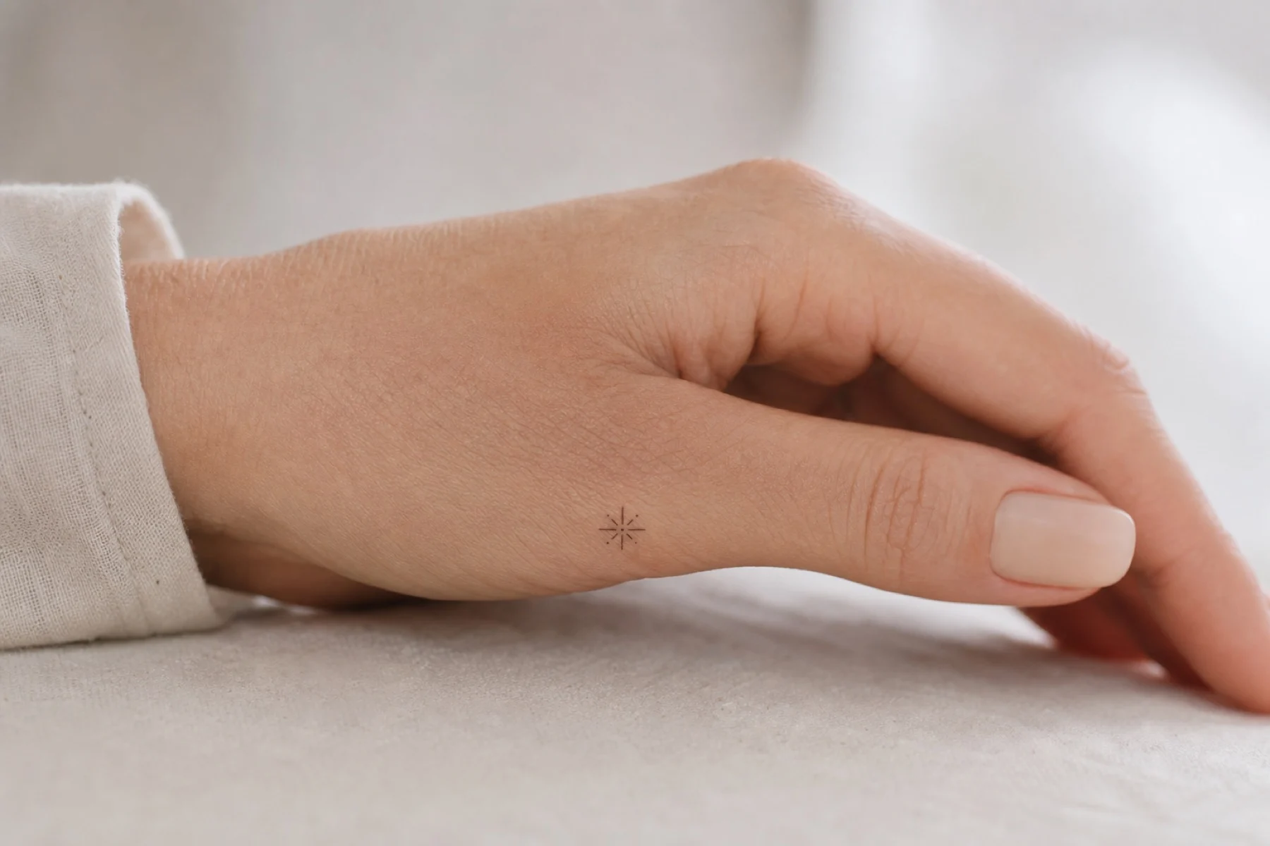 Tatuagem feminina na mão vista de lado com traço fino e discreto