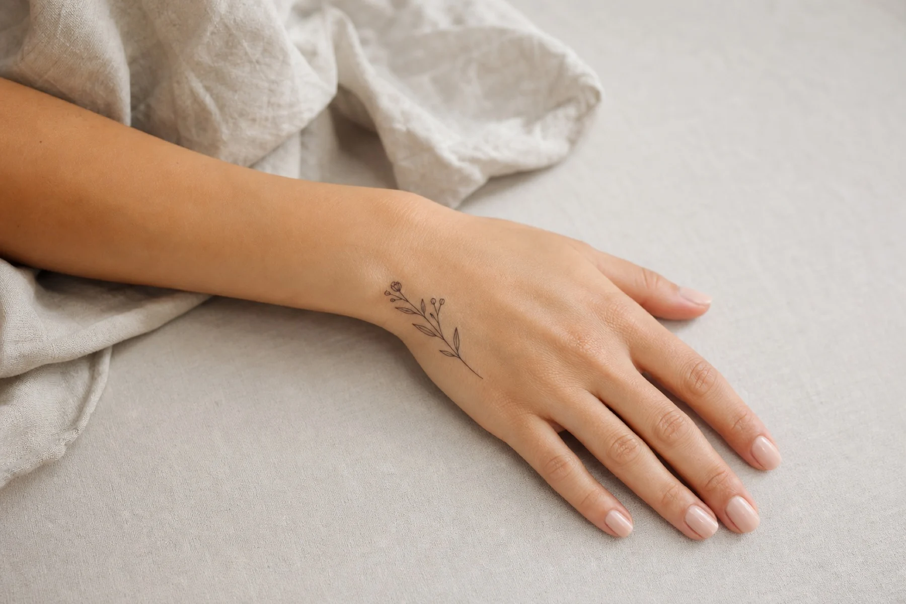 Tatuagem pequena e floral no dorso da mão de uma mulher adulta