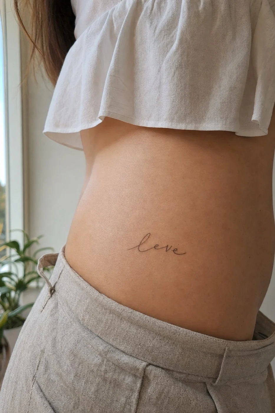 Tatuagem feminina no quadril com frase delicada em traço fino