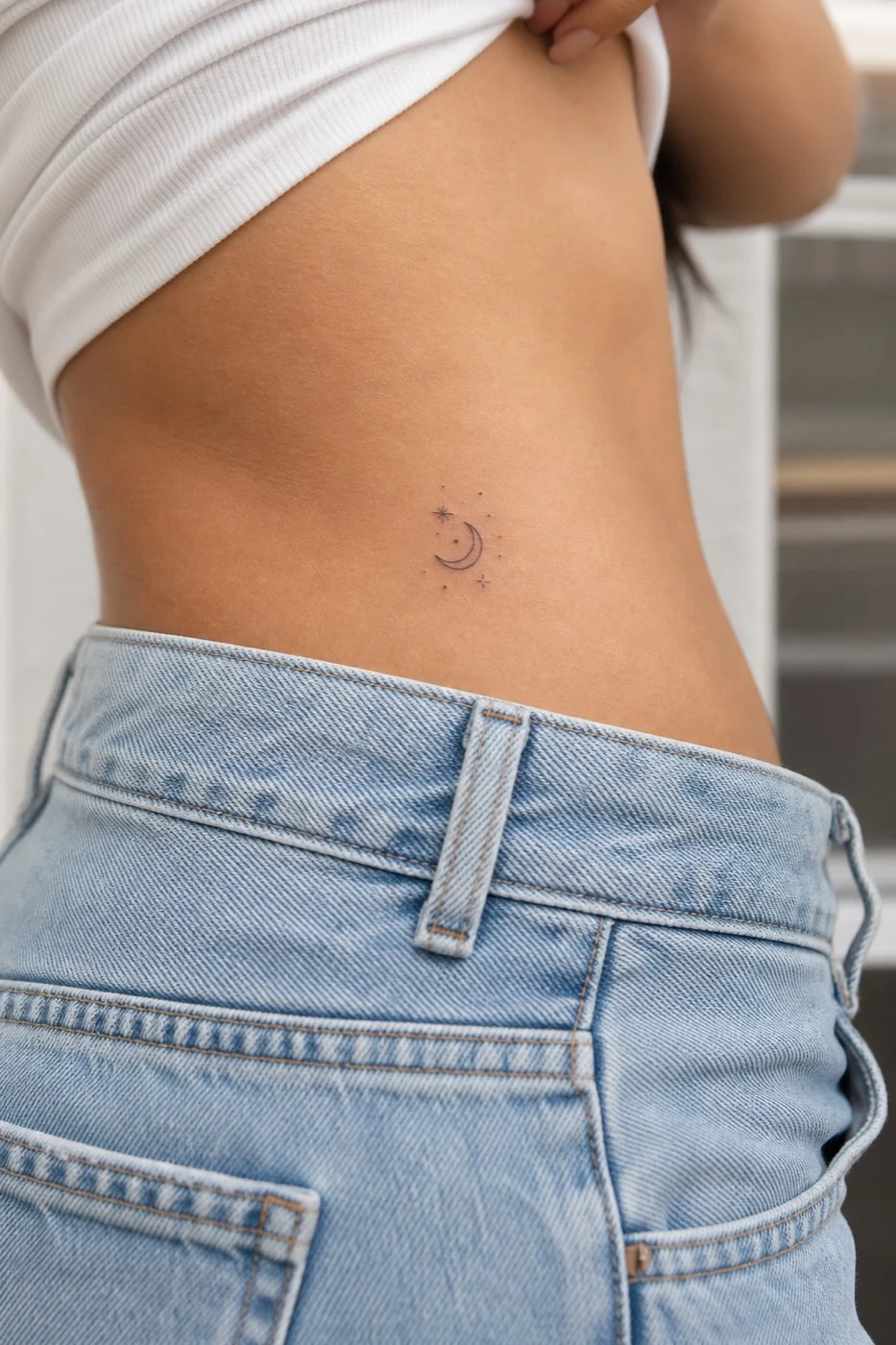 Tatuagem feminina no quadril com lua e estrelas em traço fino