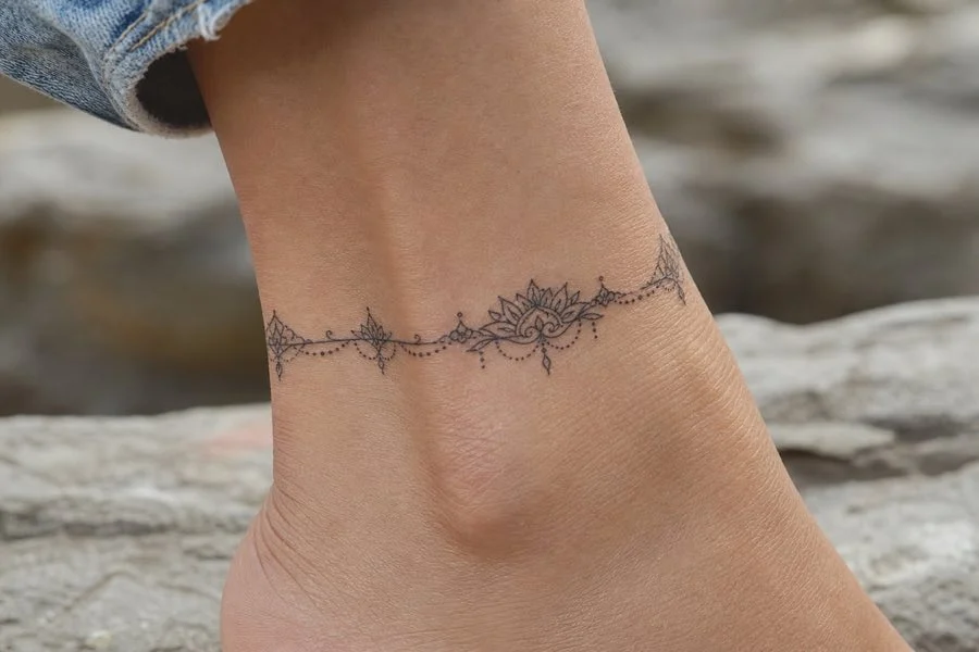 Tatuagem feminina no tornozelo com flores delicadas em fine line
