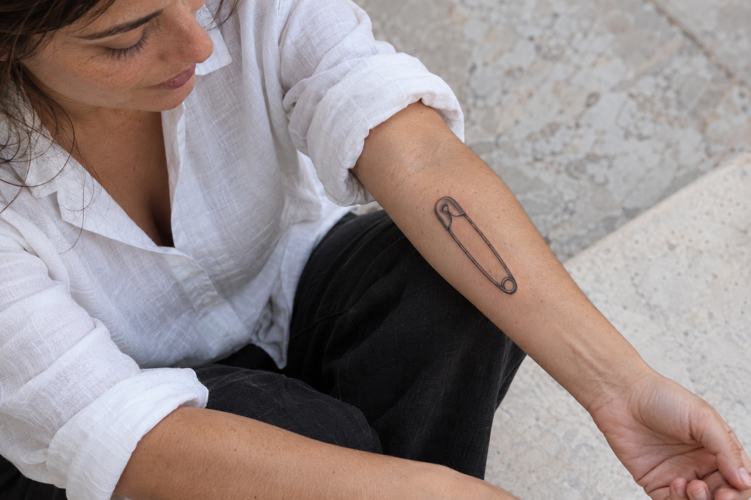 Alfinete de segurança de contorno preto no antebraço feminino