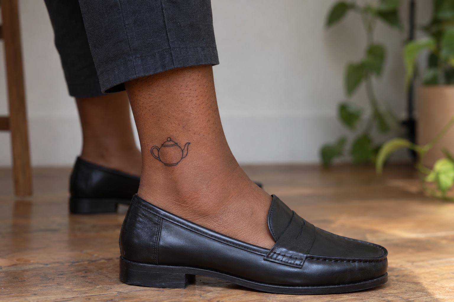 Pequeno bule de contorno preto tatuado acima do tornozelo de mulher adulta