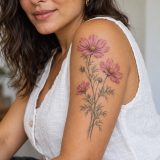 Três flores de cosmos rosadas com folhas finas no braço de mulher adulta