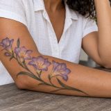 Ramo de frésias em lavanda com flores abertas e botões no braço feminino
