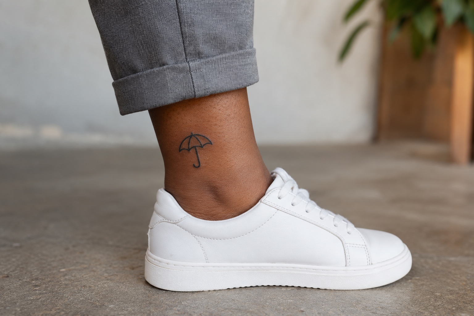 Guarda-chuva pequeno de contorno preto tatuado acima do tornozelo de mulher adulta