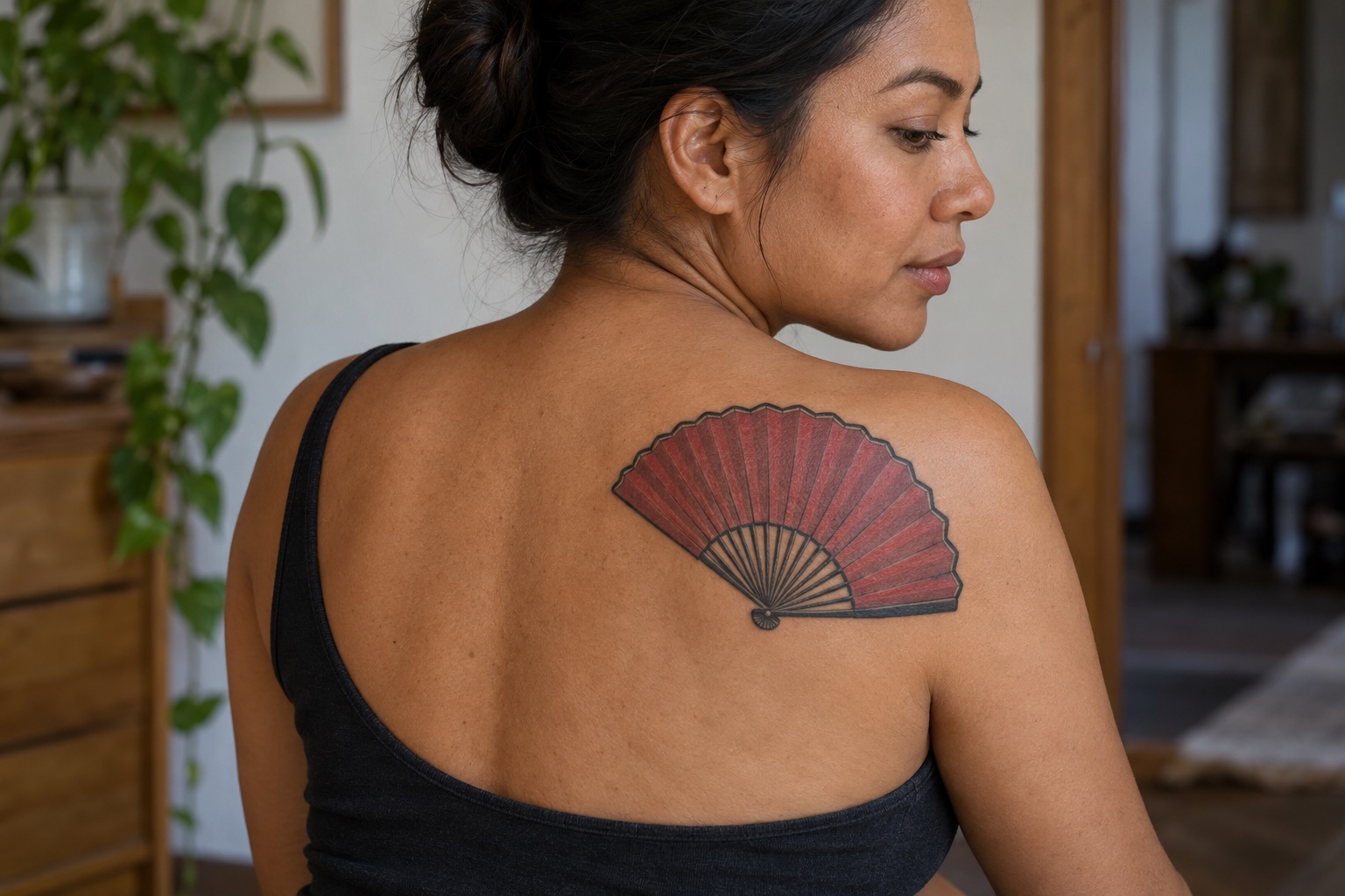 Leque vermelho e preto tatuado nas costas superiores de mulher adulta